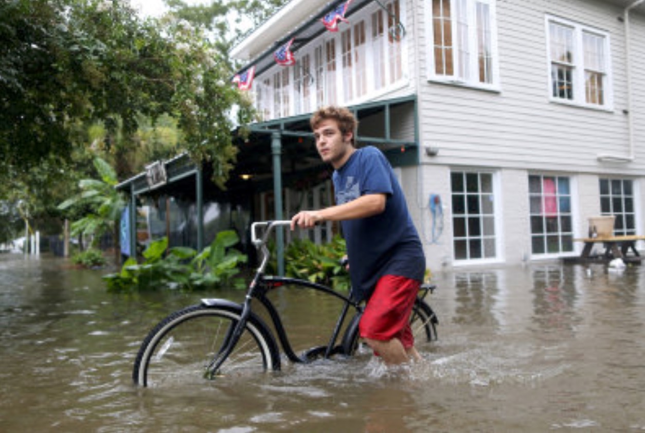Ódnin Barry hevur floymt gøturnar í fleiri býum í statinum Lousiana í USA. Her sæst ein maður leiða súkkluna gjøgnug í býnum Mandeville. Mynd: Jonathan Bachman/Reuters